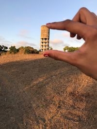 Optical illusion of woman holding water tank against sky