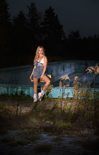 Portrait of young woman sitting by abandoned swimming pool