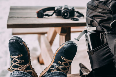 Low section of man by backpack on bench 