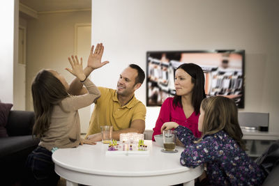 Father and daughter giving high-five while playing ludo at coffee table