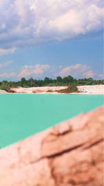 Swimming pool by sea against sky