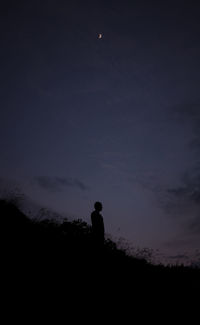 Silhouette man standing on field against sky at night