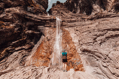 Rear view of man walking on rock with mountain in background