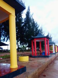 Red bell tower by trees against sky