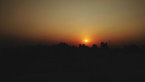 Silhouette cityscape against clear sky during sunset