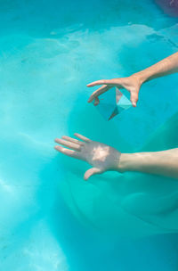 Cropped hand of woman holding pyramid crystal in swimming pool