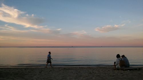 Man standing on beach against sky during sunset