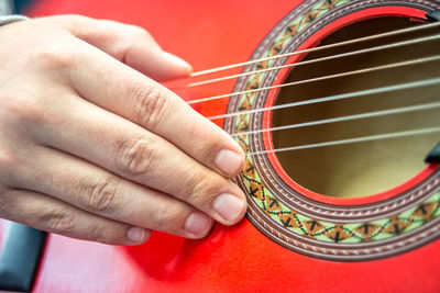 Close-up of human hand playing red guitar