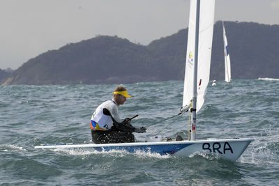 Man in boat on sea against mountain