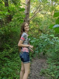 Portrait of smiling young woman standing in forest