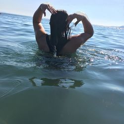 Young woman in bikini standing by sea against sky