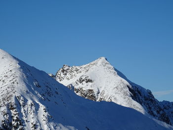 Scenic view of snowcapped mountains against clear blue sky