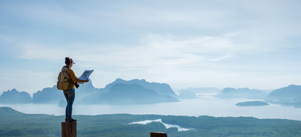 Rear view of man standing on mountain against sky