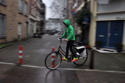 Boy riding bicycle on street in city