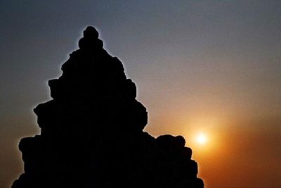 Silhouette statue against sky at sunset