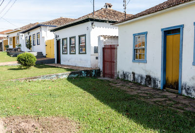 Houses on field by buildings against sky