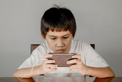 Portrait of boy holding food against white background