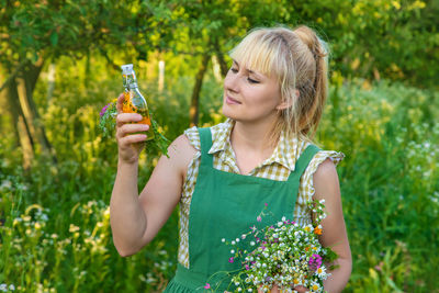 Young woman blowing bubbles while standing against plants