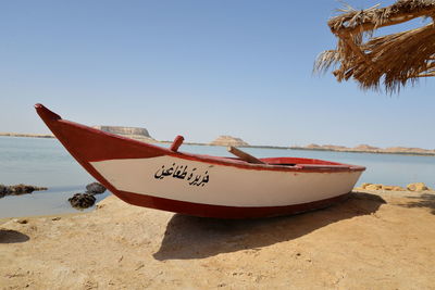 Boat moored on beach against clear sky