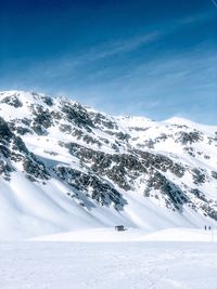 Scenic view of snow covered mountains against blue sky