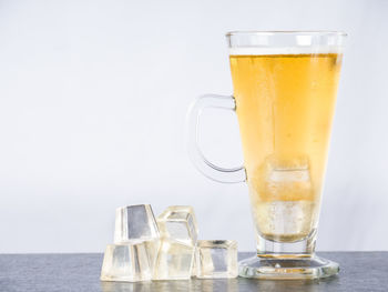 Glass of beer on table against white background