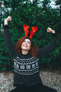 Smiling young woman against trees