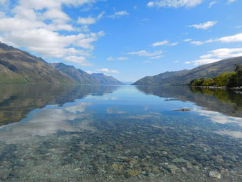 Scenic view of lake and mountains against blue sky