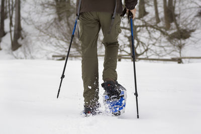 Low section of person walking on snow covered land