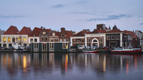 Buildings by lake against sky in city