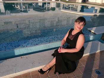 Portrait of young woman standing by railing