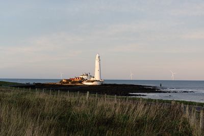 Lighthouse by sea against sky