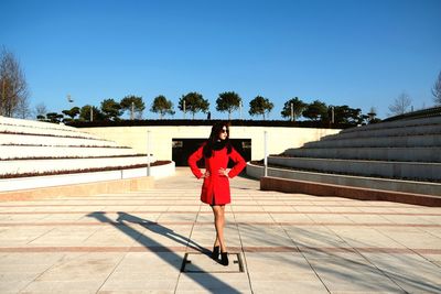 Woman standing amidst steps in city against clear blue sky