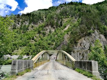 Footbridge amidst trees against sky