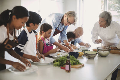 Senior woman guiding family in preparing asian food in kitchen