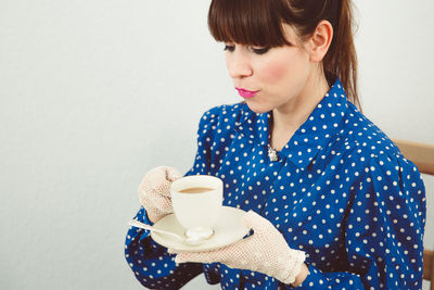 Close-up of woman holding coffee cup over white background