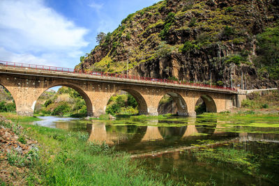 Arch bridge over river against sky