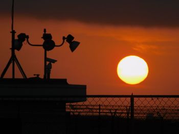 Silhouette fence against orange sky