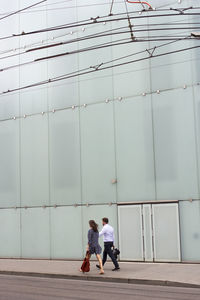 Friends walking on sidewalk against building