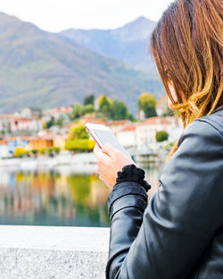 Rear view of woman photographing by mountain against sky