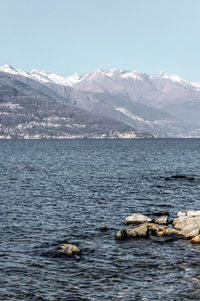 Scenic view of sea and snowcapped mountains against sky