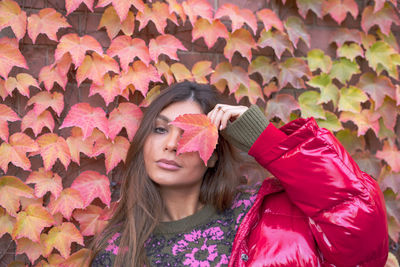 Portrait of woman with pink leaves during autumn