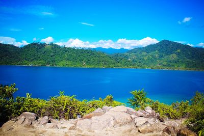 Scenic view of lake and mountains against blue sky