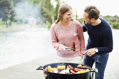 Happy couple looking at each other while barbecuing on pier