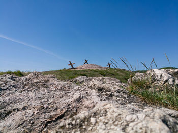 Low angle view of rocks on mountain against clear blue sky