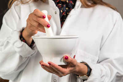 Midsection of doctor holding mortar and pestle