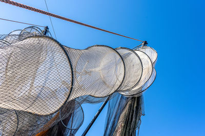 Low angle view of fishing net against clear blue sky