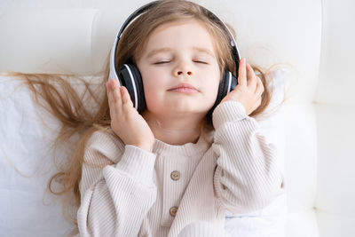 Cute girl listening music while lying on bed