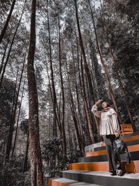 Woman standing by tree trunk in forest