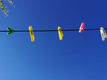 Low angle view of flags hanging against clear blue sky