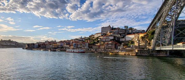 Buildings by river against sky in town